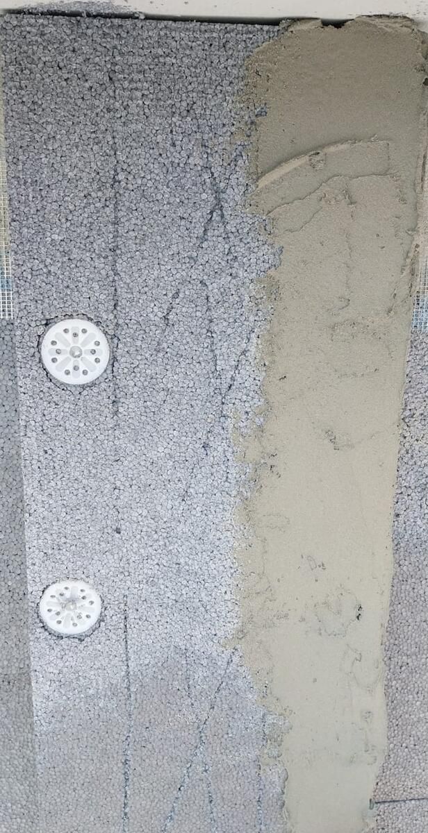 Dettaglio ravvicinato dei tasselli a fungo che fissano i pannelli isolanti alla muratura.