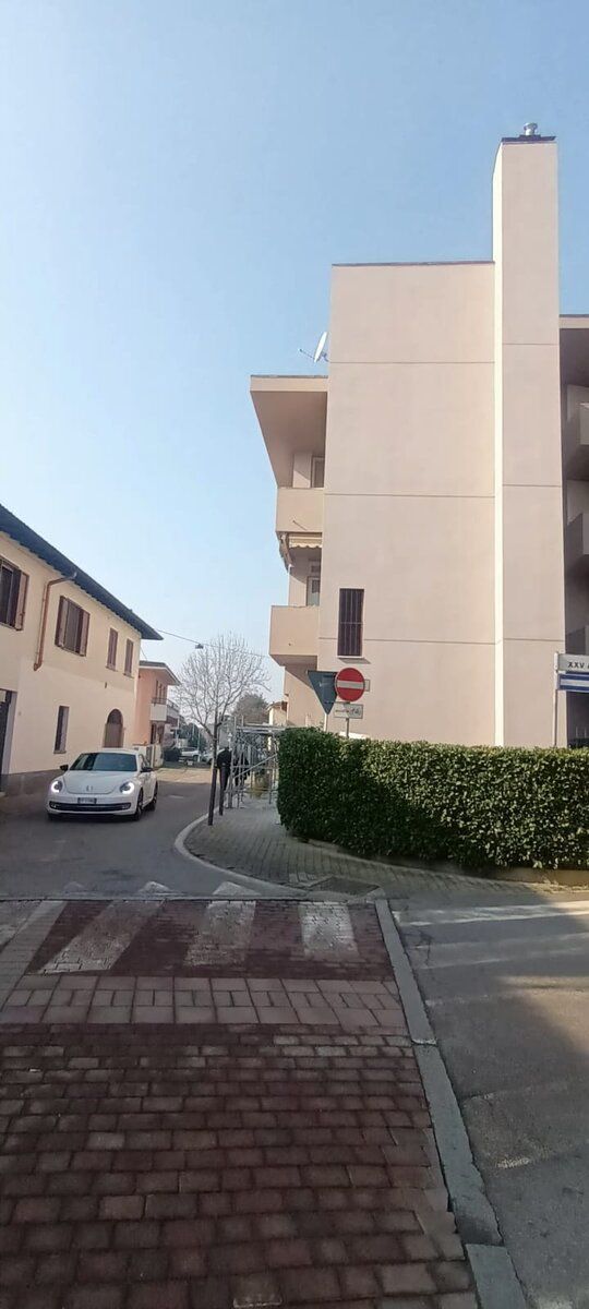 Fronte strada di edificio residenziale a lavori finiti, con marciapiede e siepe.