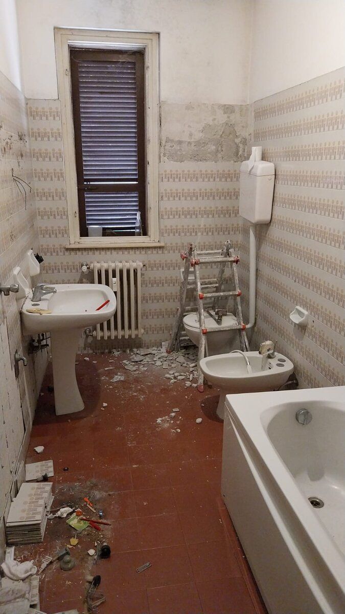 Bagno demolito, con le macerie a terra e gli attacchi degli impianti a vista.