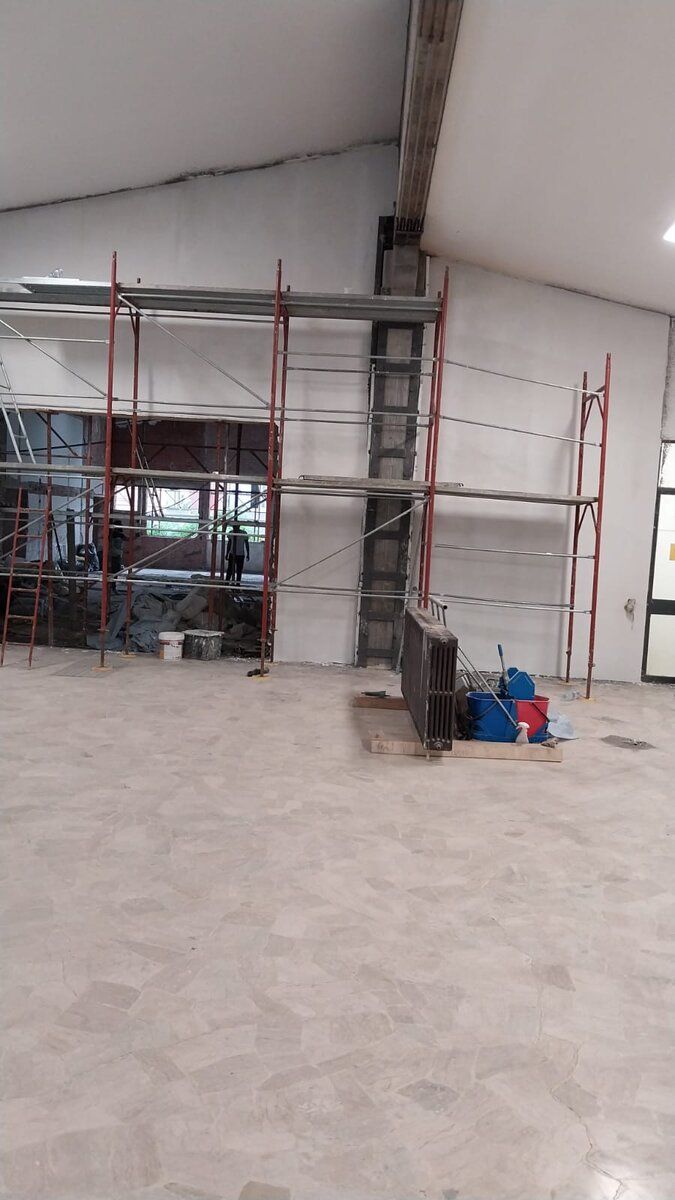 Ambiente ampio con ponteggio interno montato e attrezzature di cantiere.