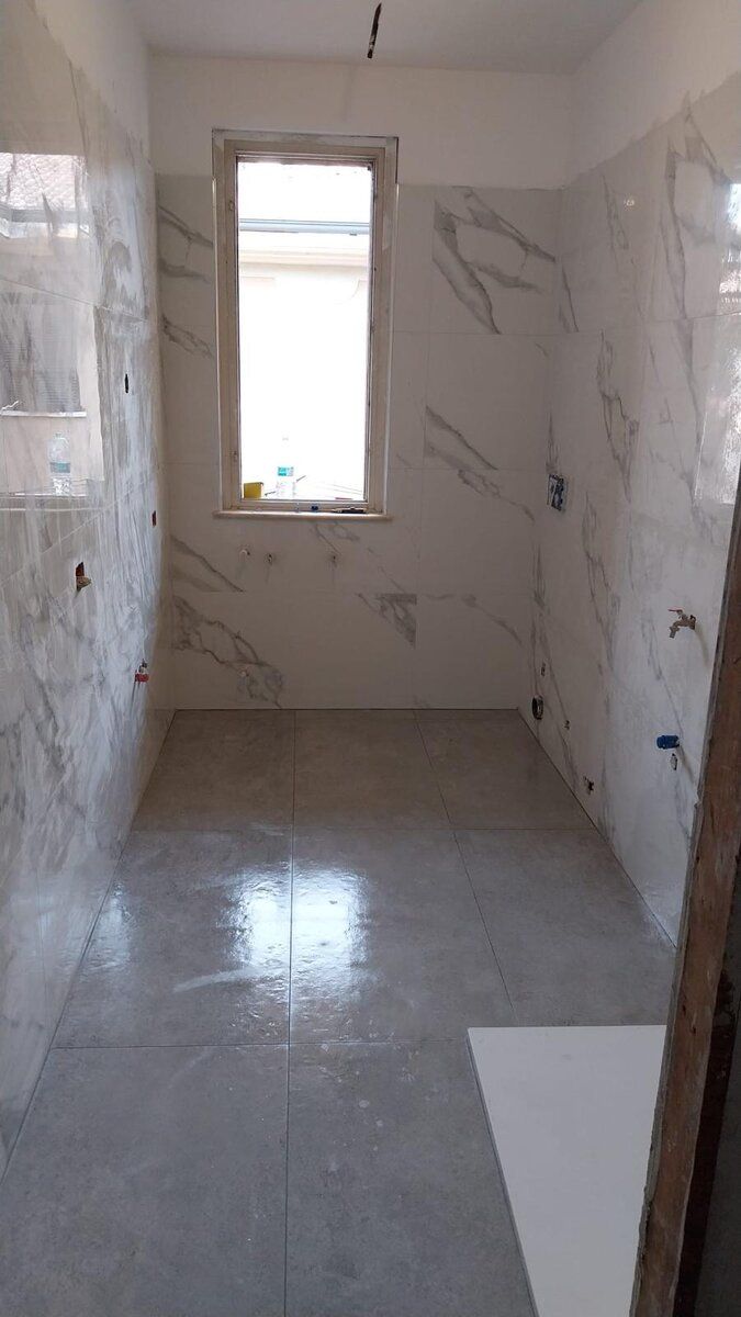Lo stesso bagno rivestito in gres effetto marmo dal pavimento al soffitto.